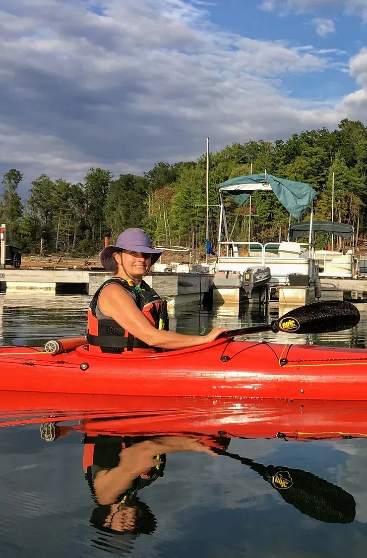 A woman is sitting in a red kayak in the water.