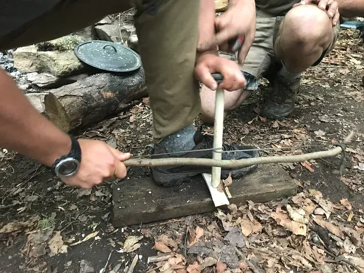 A person is cutting a stick with a saw.