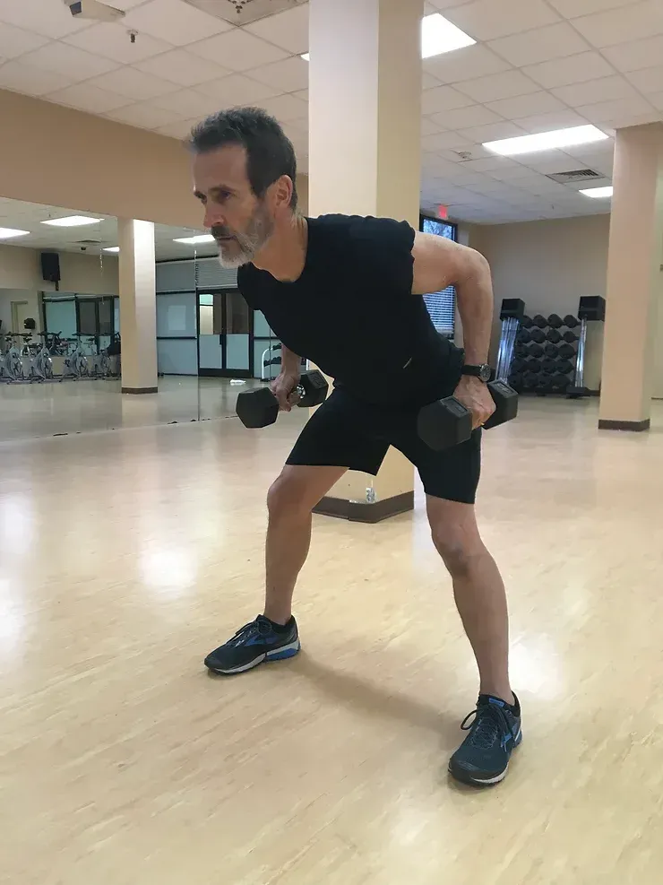 A man is lifting a dumbbell in a gym.