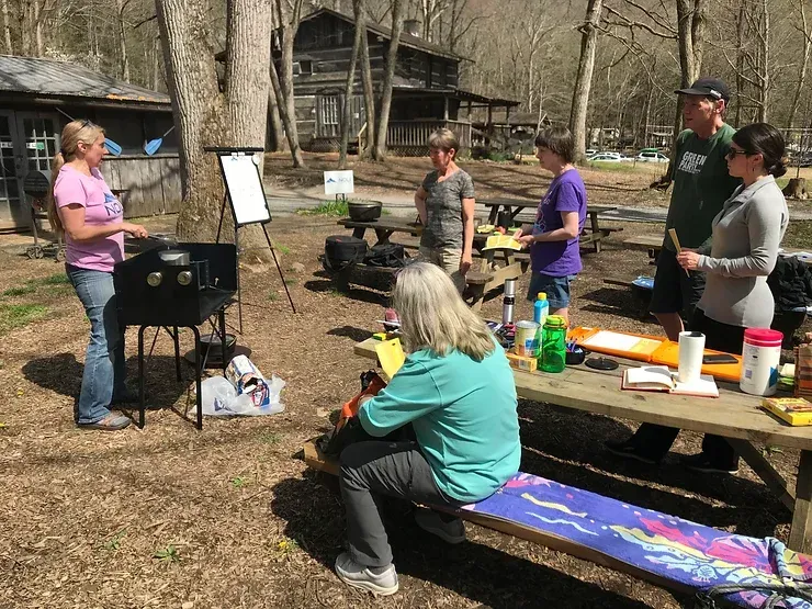 A group of people are sitting at a picnic table in a park.