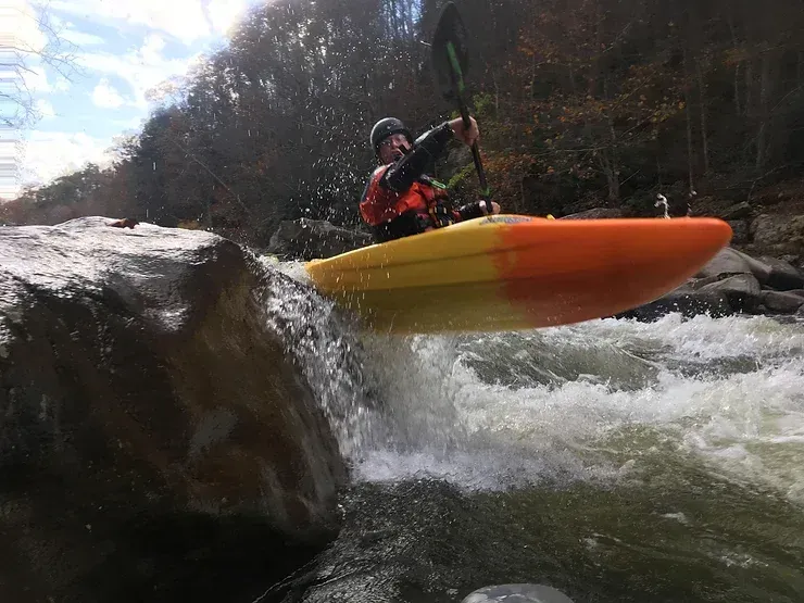 A man is riding a kayak down a river.