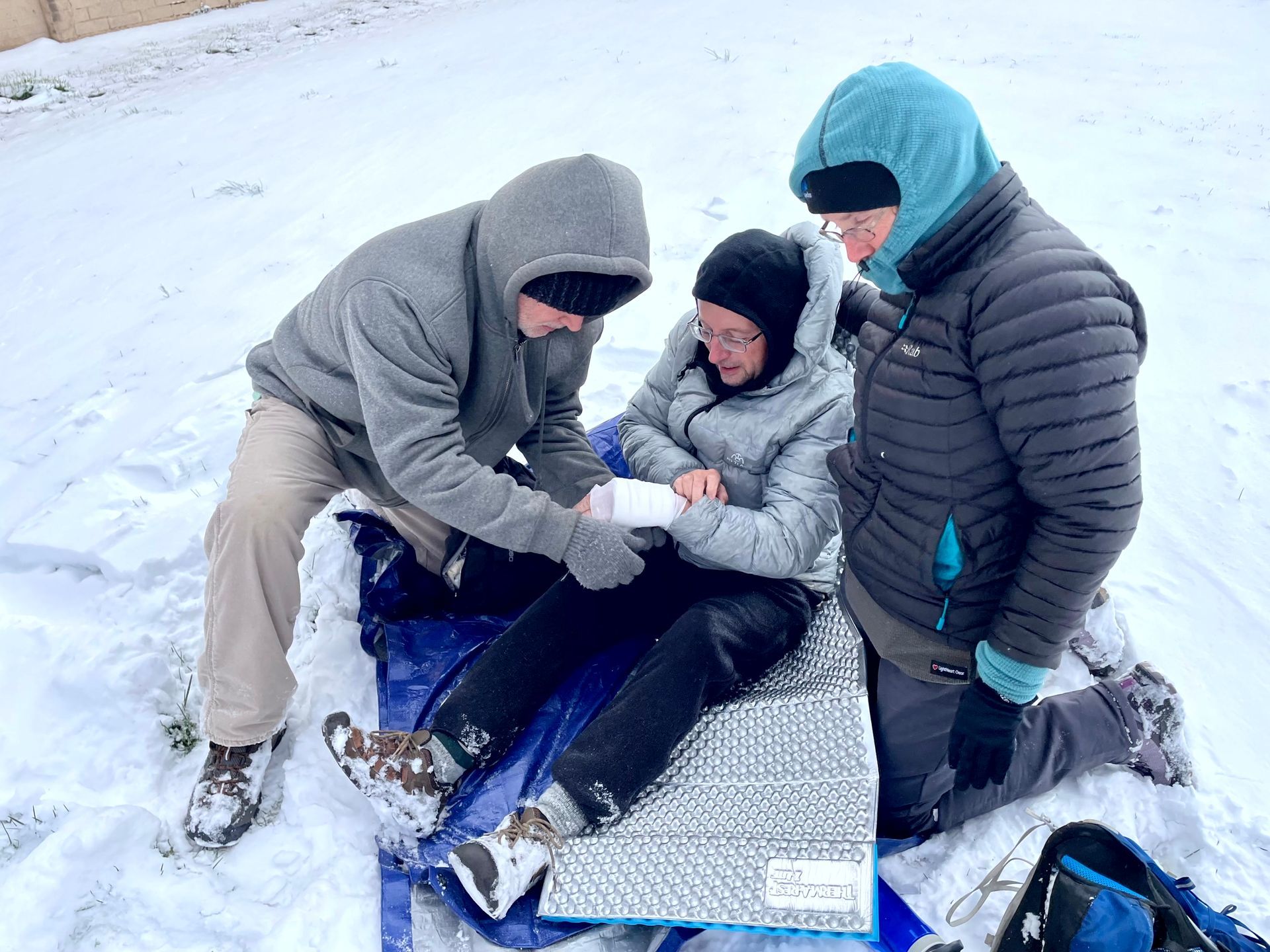 A group of people are helping a person in the snow.