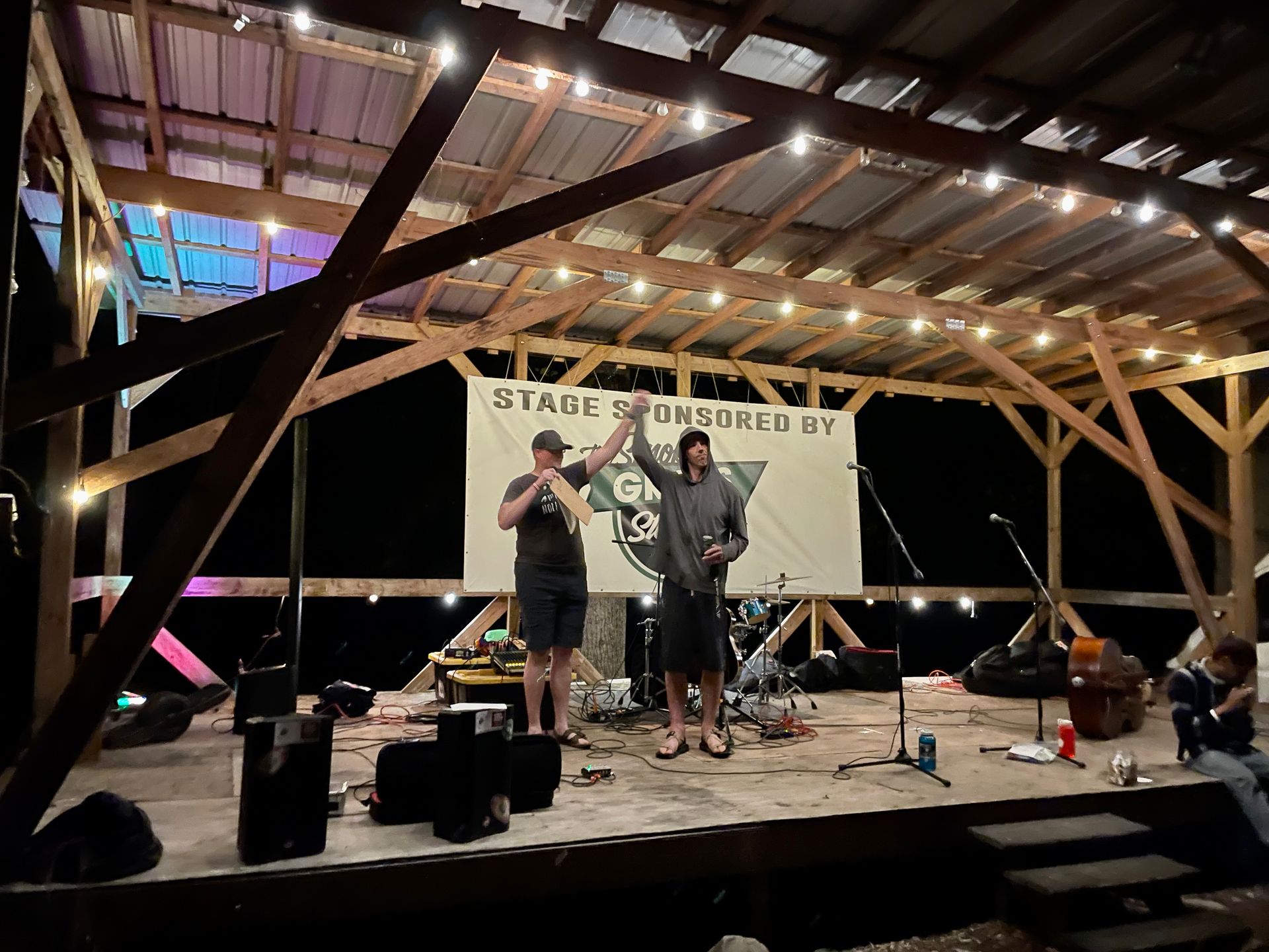 Two men are standing on a stage in front of a sign that says stage powered by.