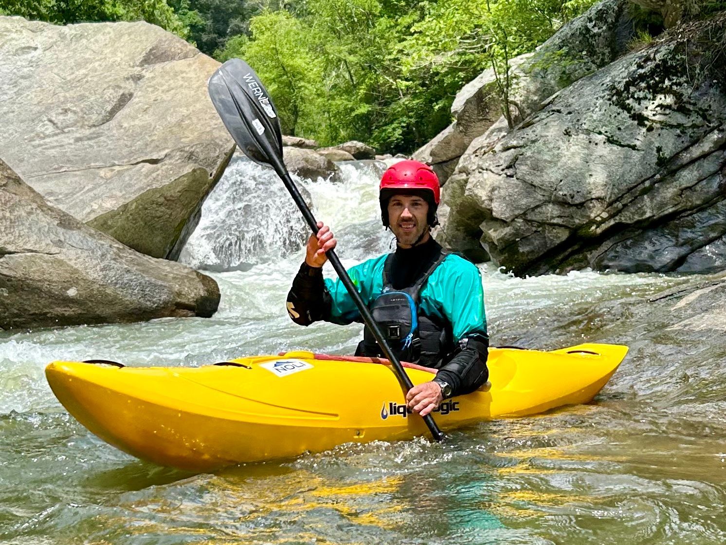 A man is sitting in a yellow kayak in a river holding a paddle.
