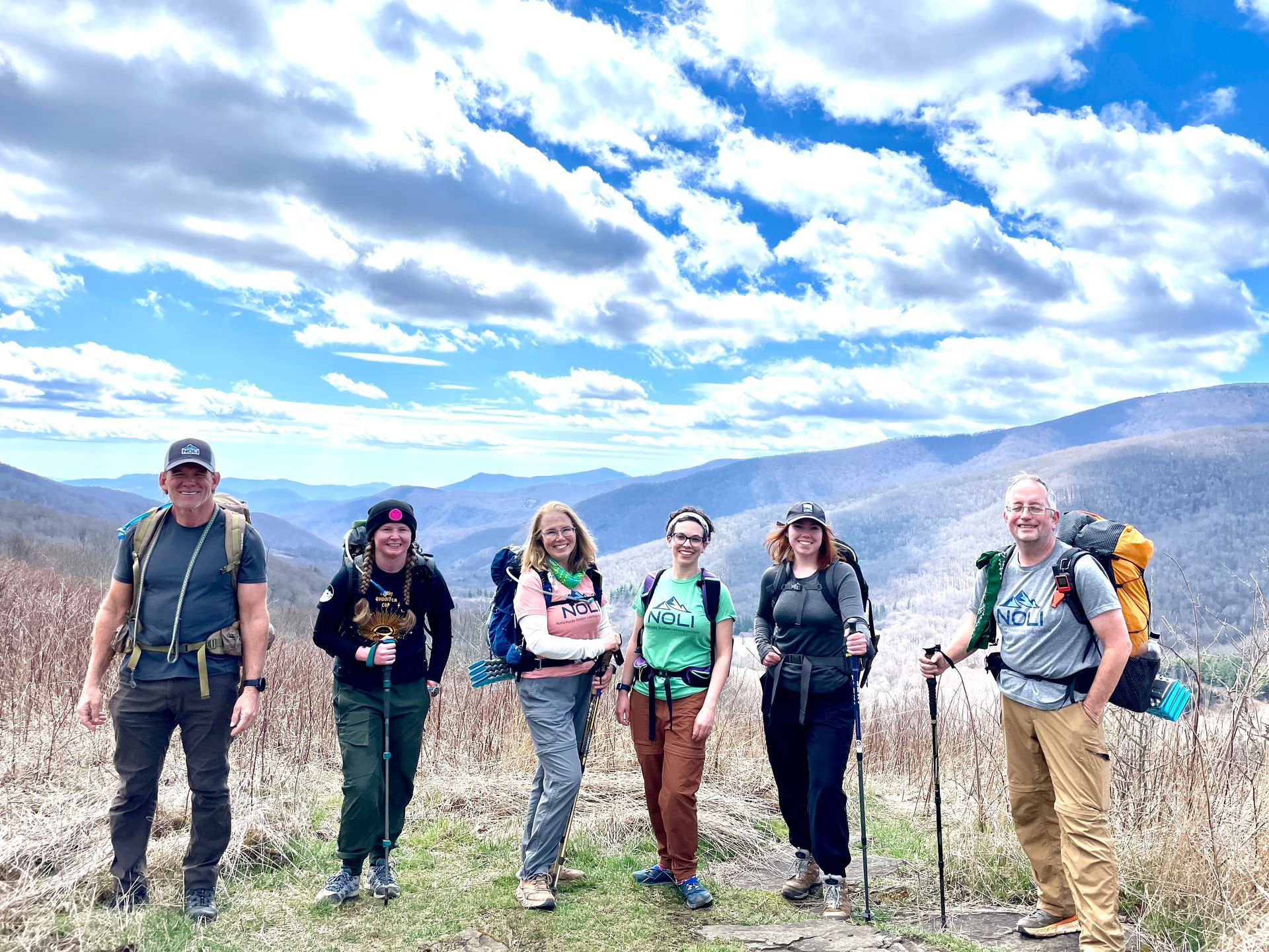 A group of people are standing next to each other on top of a mountain.