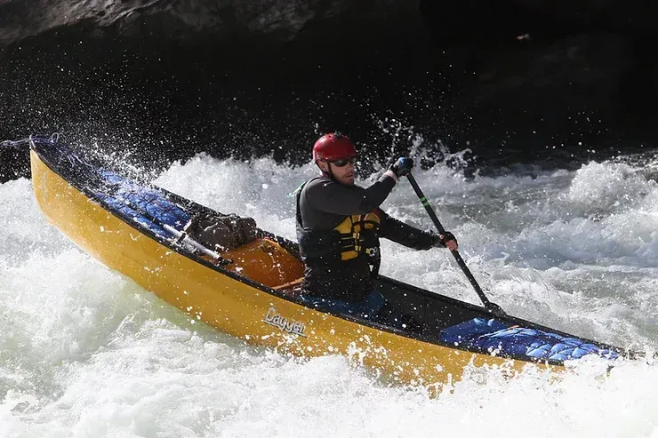 A man is paddling a kayak through a river.