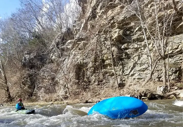 A person is paddling a blue raft down a river.