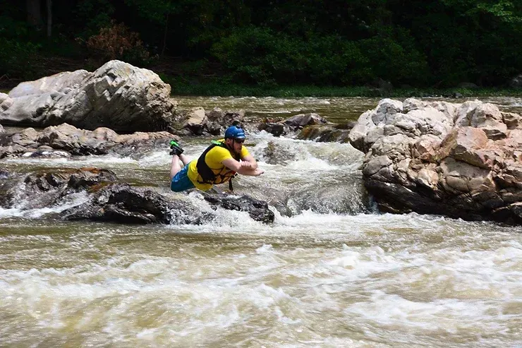 A man is laying on a rock in a river.