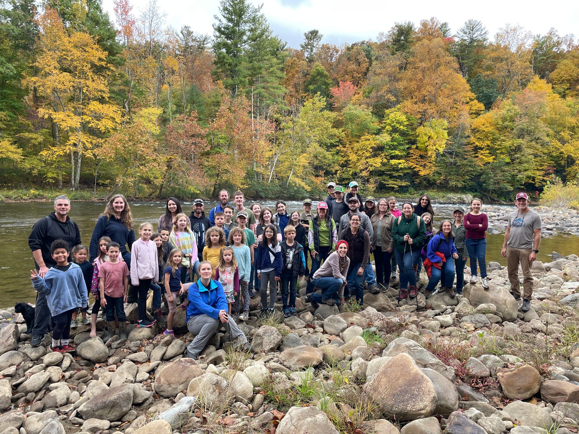 A large group of people are posing for a picture in front of a river.