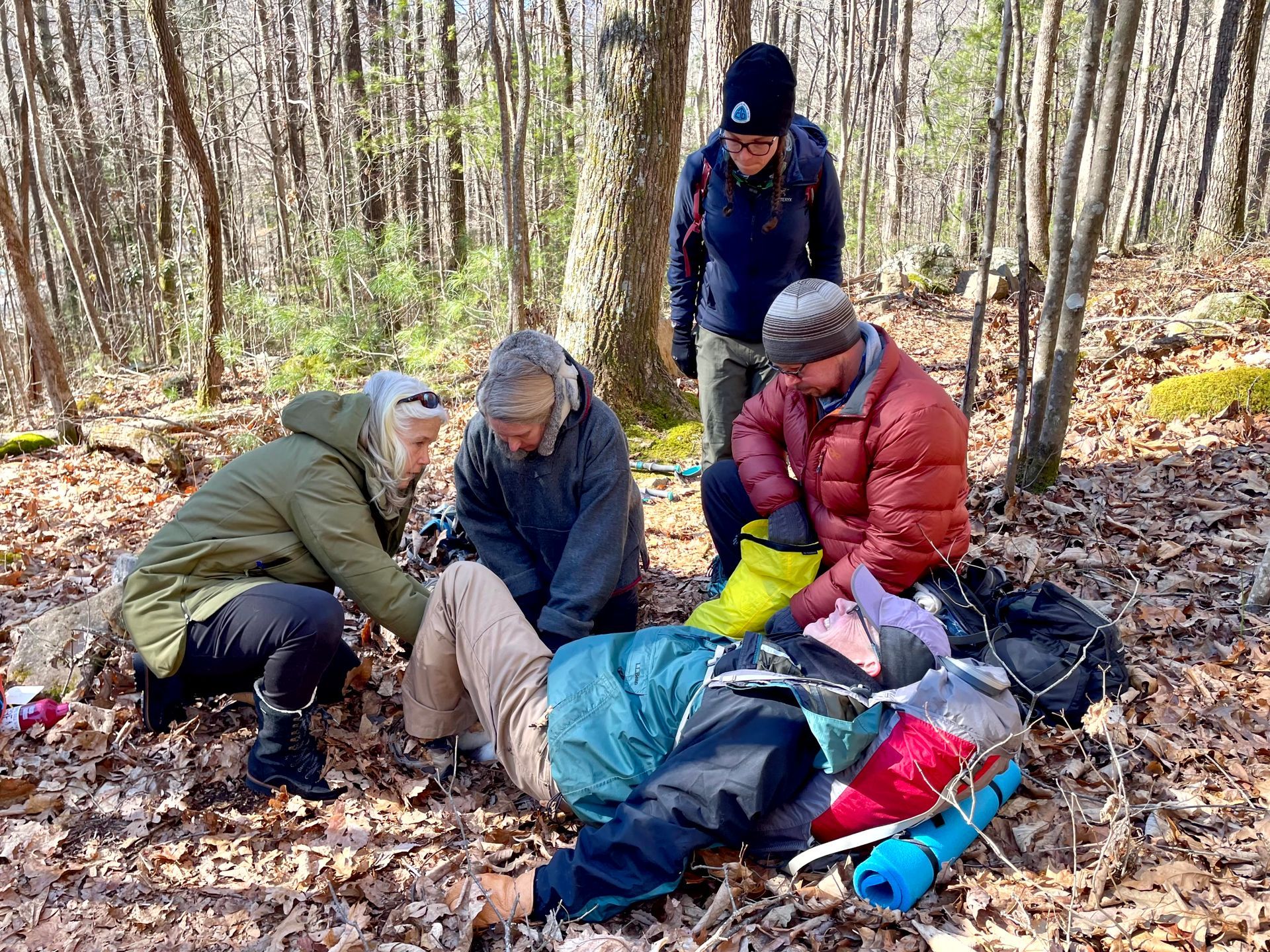 A group of people are helping a person in the woods.