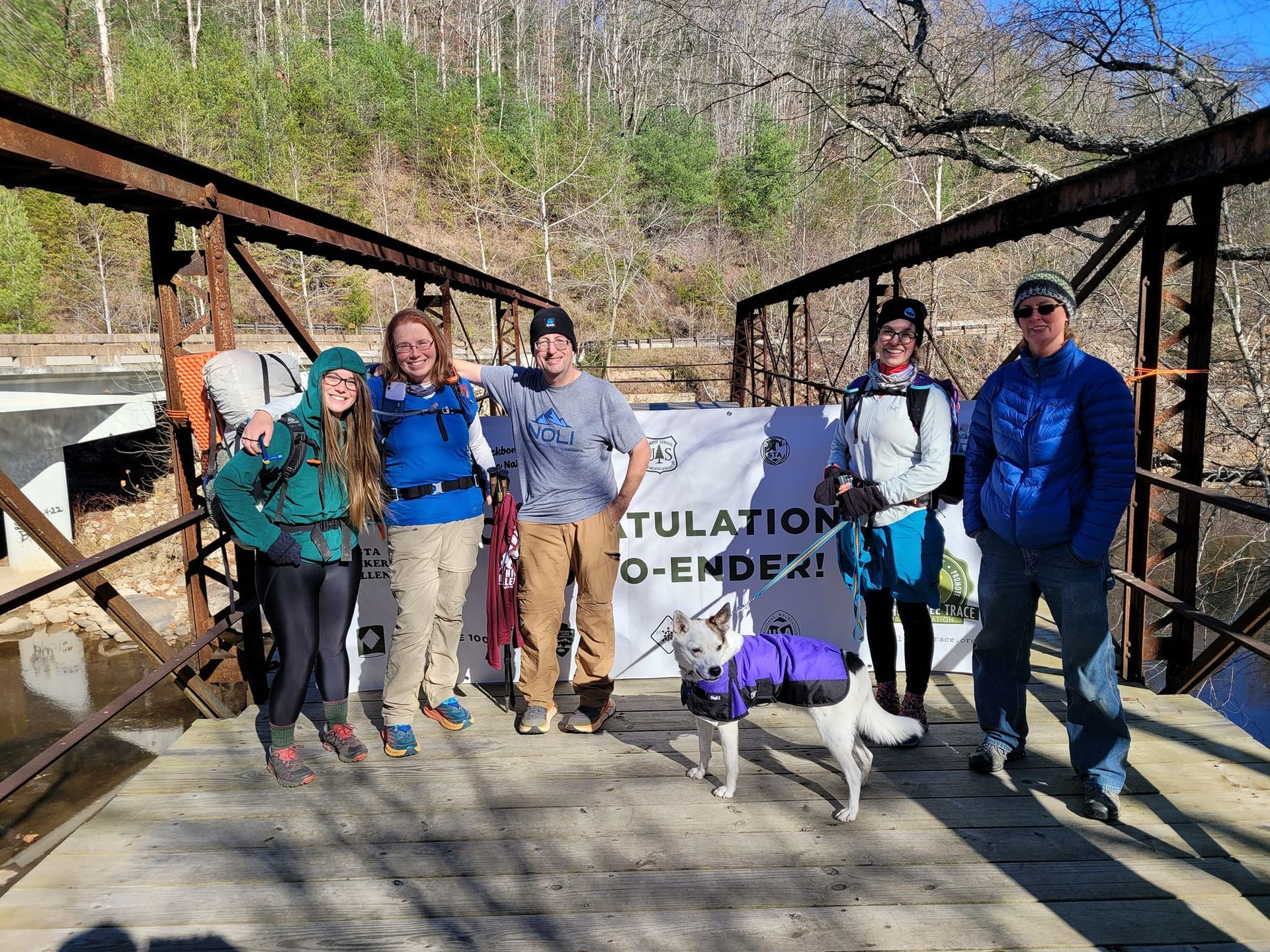 A group of people and a dog are posing for a picture on a bridge.
