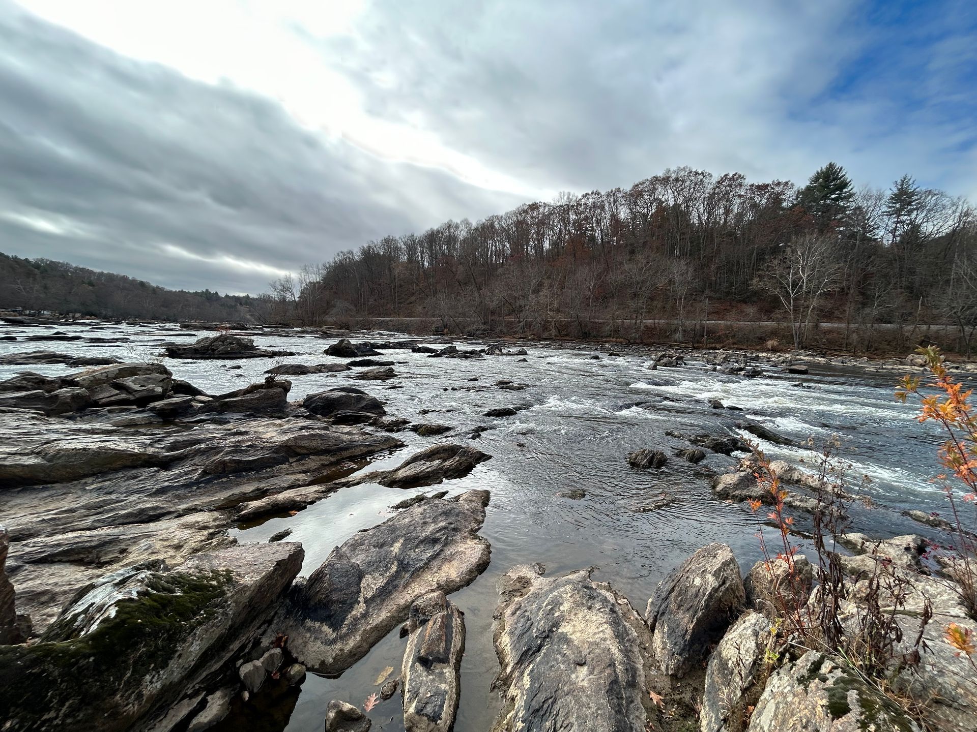 A river surrounded by rocks and trees on a cloudy day