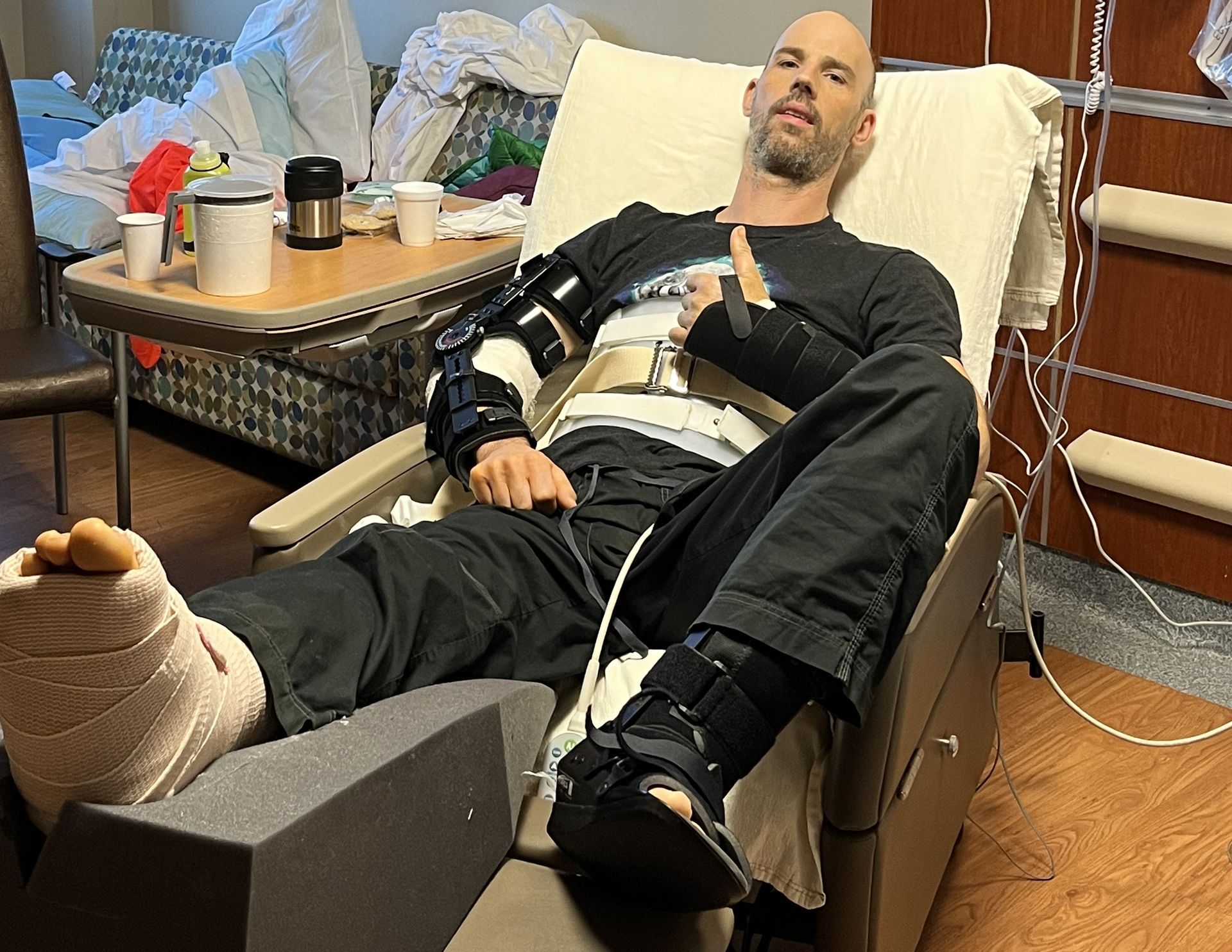 A man with a broken leg is laying in a hospital bed.
