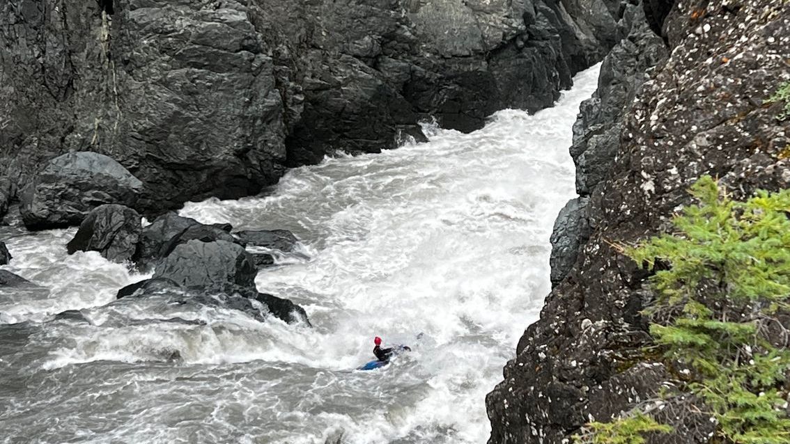 A person in a kayak is going down a river.