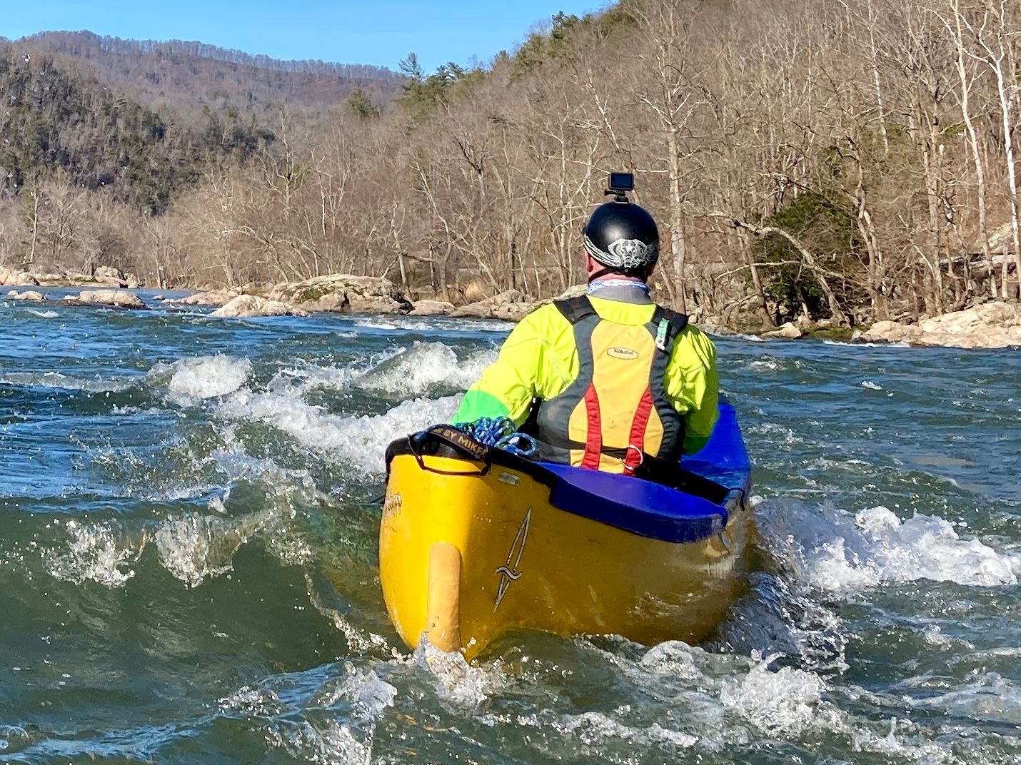 A man is riding a yellow kayak down a river.