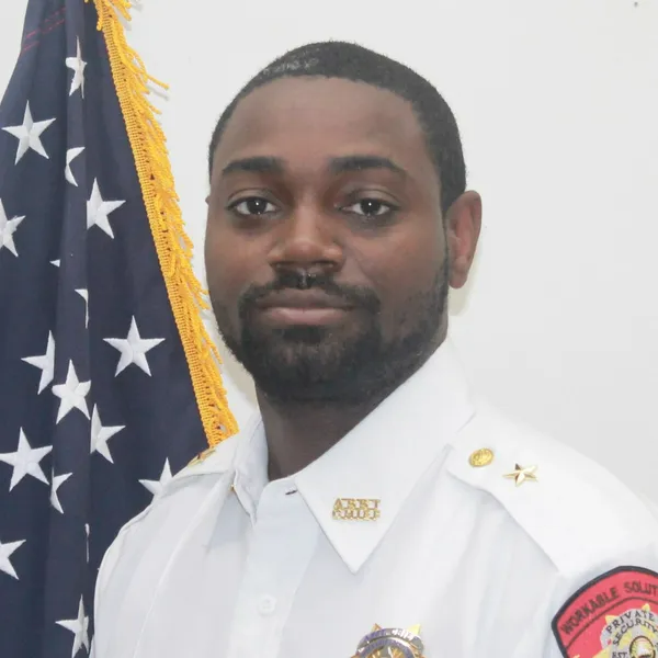 Portrait of a uniformed officer in white beside an American flag