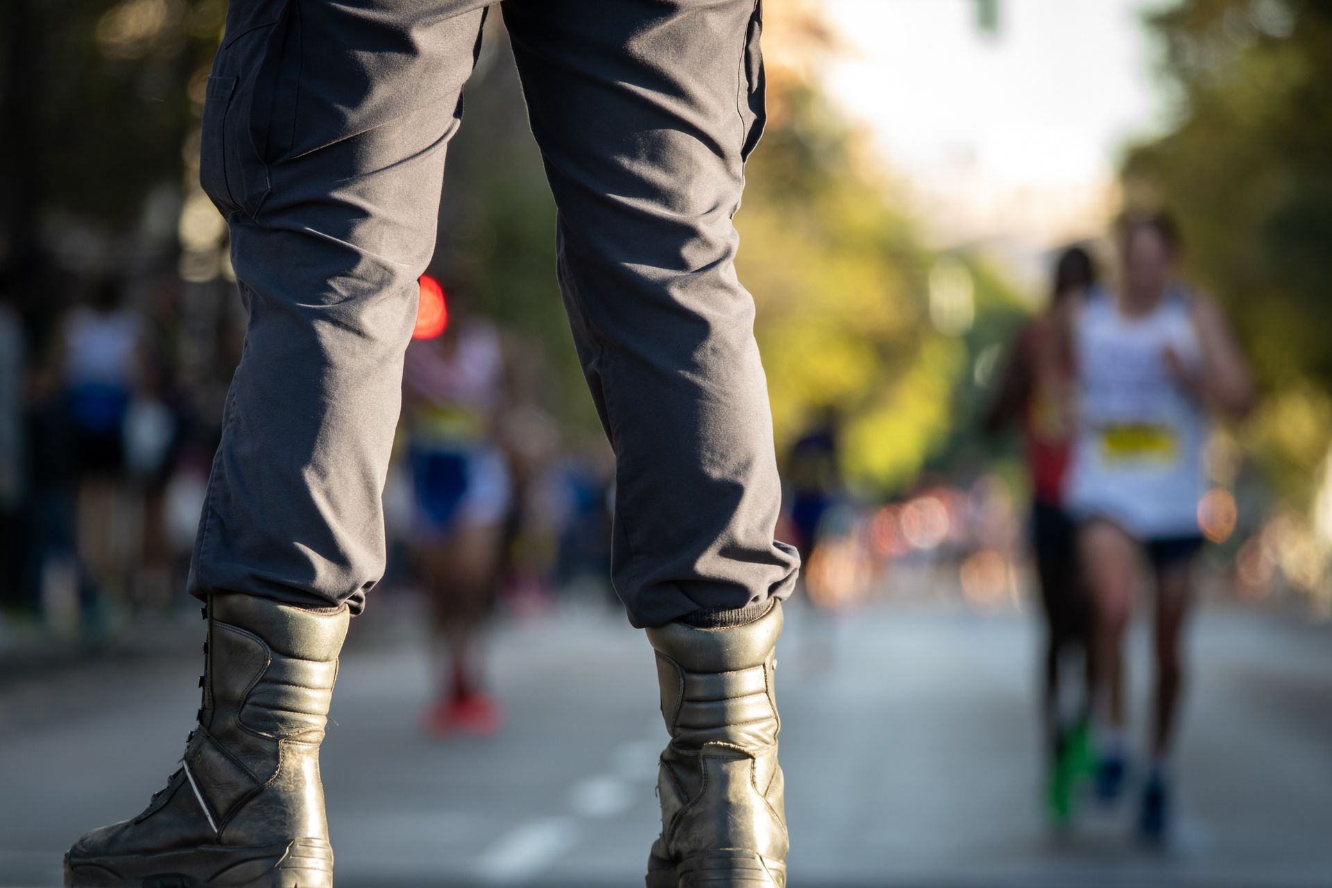 Close-up of a runner’s legs in gray pants and boots on a city street during a race