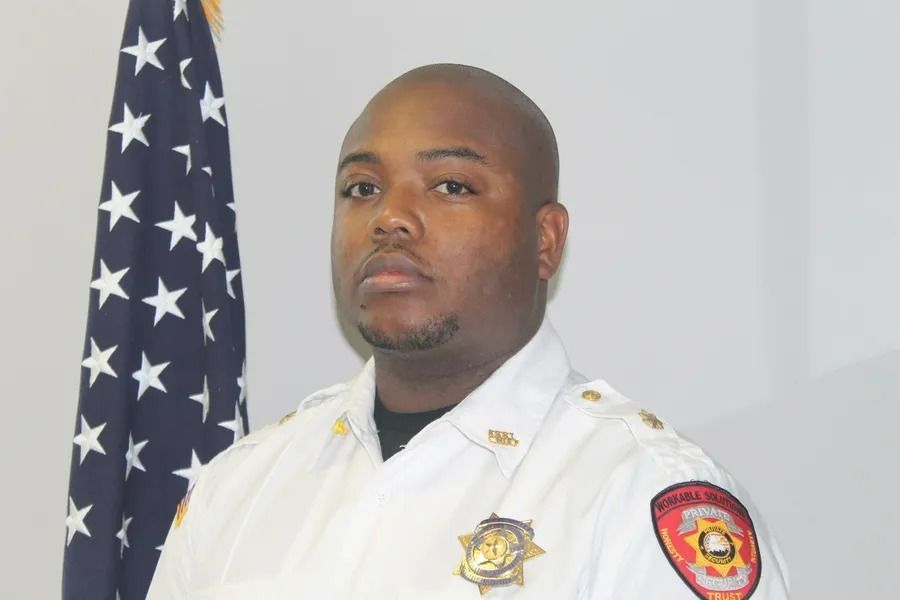 Uniformed officer standing beside an American flag, facing forward in a formal portrait.