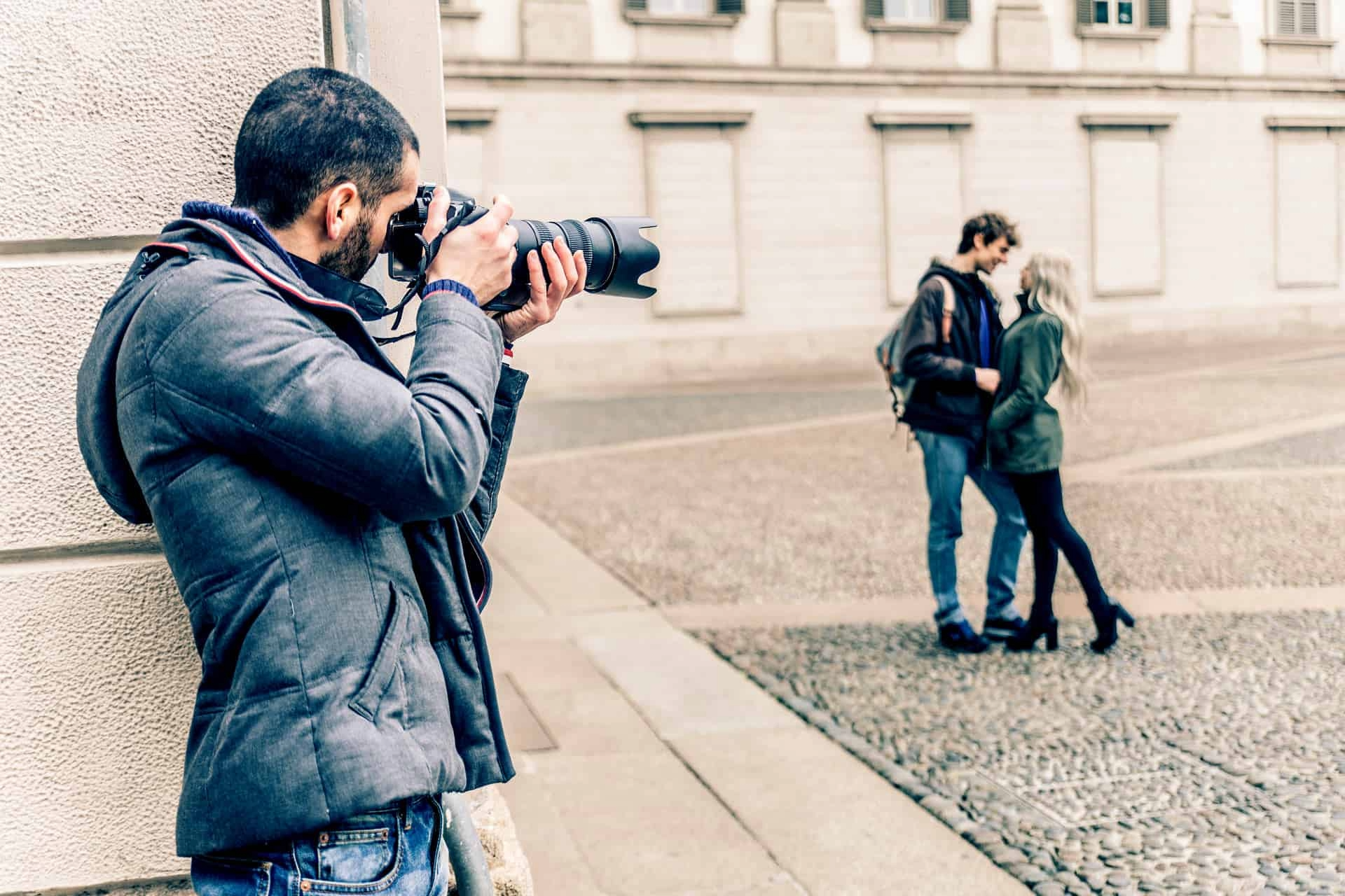 Photographer taking a shot of a couple embracing in a courtyard outside a building