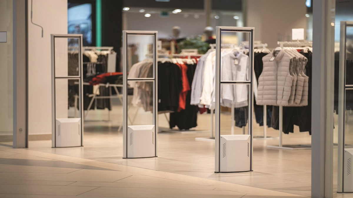 Clothing store entrance with security gates and racks of jackets and shirts inside