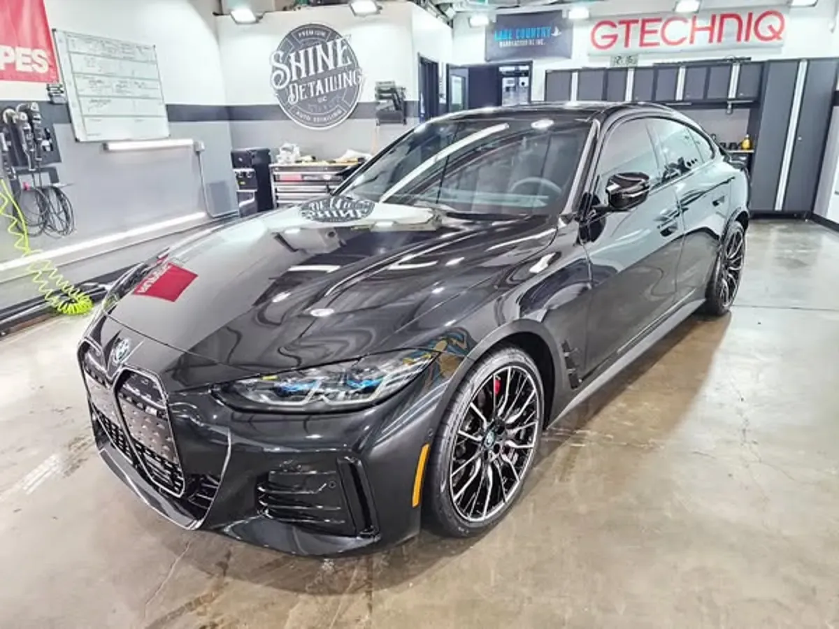 Black BMW sedan in an auto detailing shop with Gtechniq signage