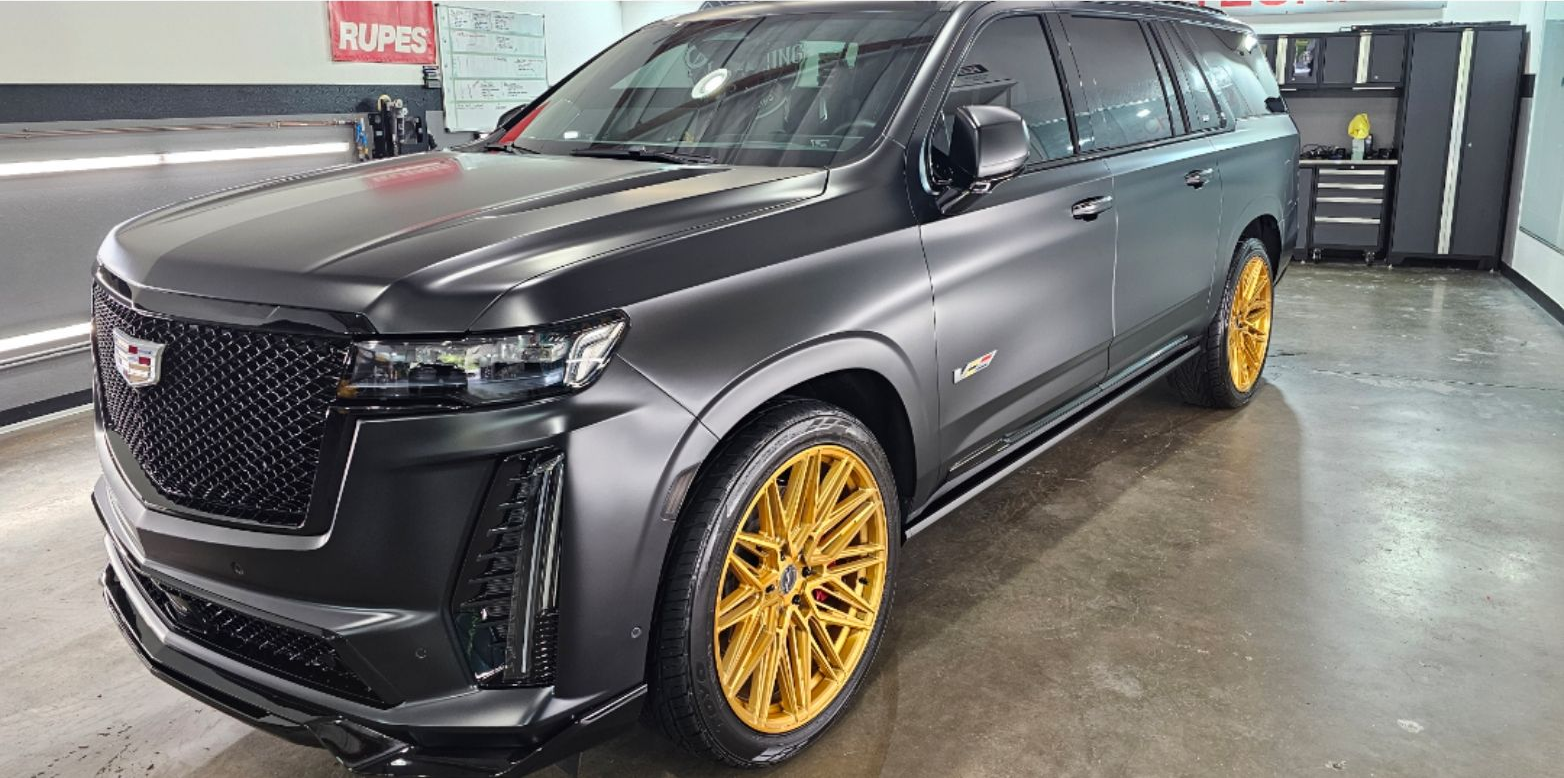 Black SUV with gold rims parked indoors in a garage or showroom