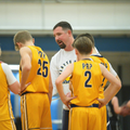 Basketball coach speaking to players in yellow jerseys during a timeout