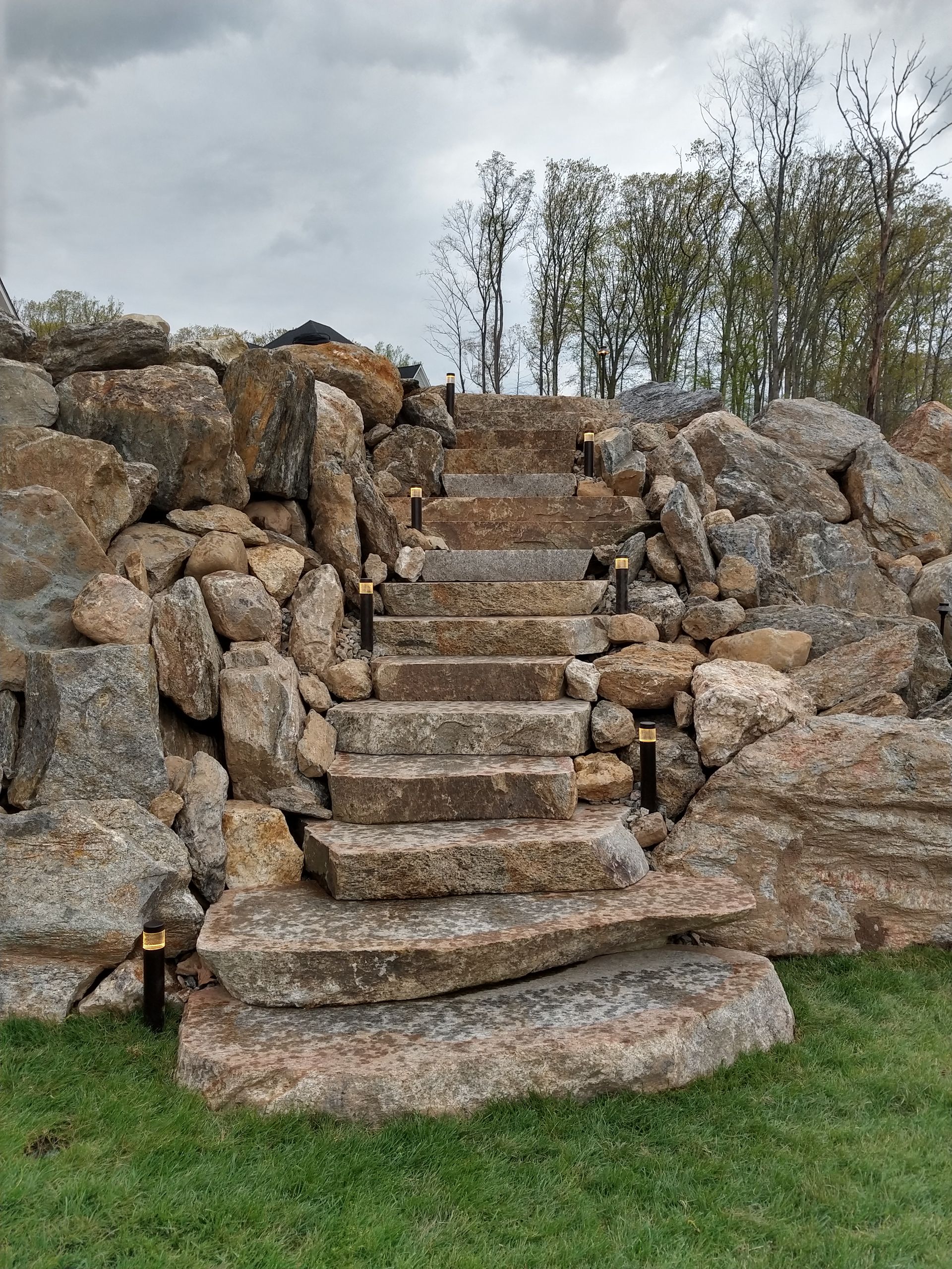 Stone steps built into a rocky hillside. Small lights illuminate the stairs.