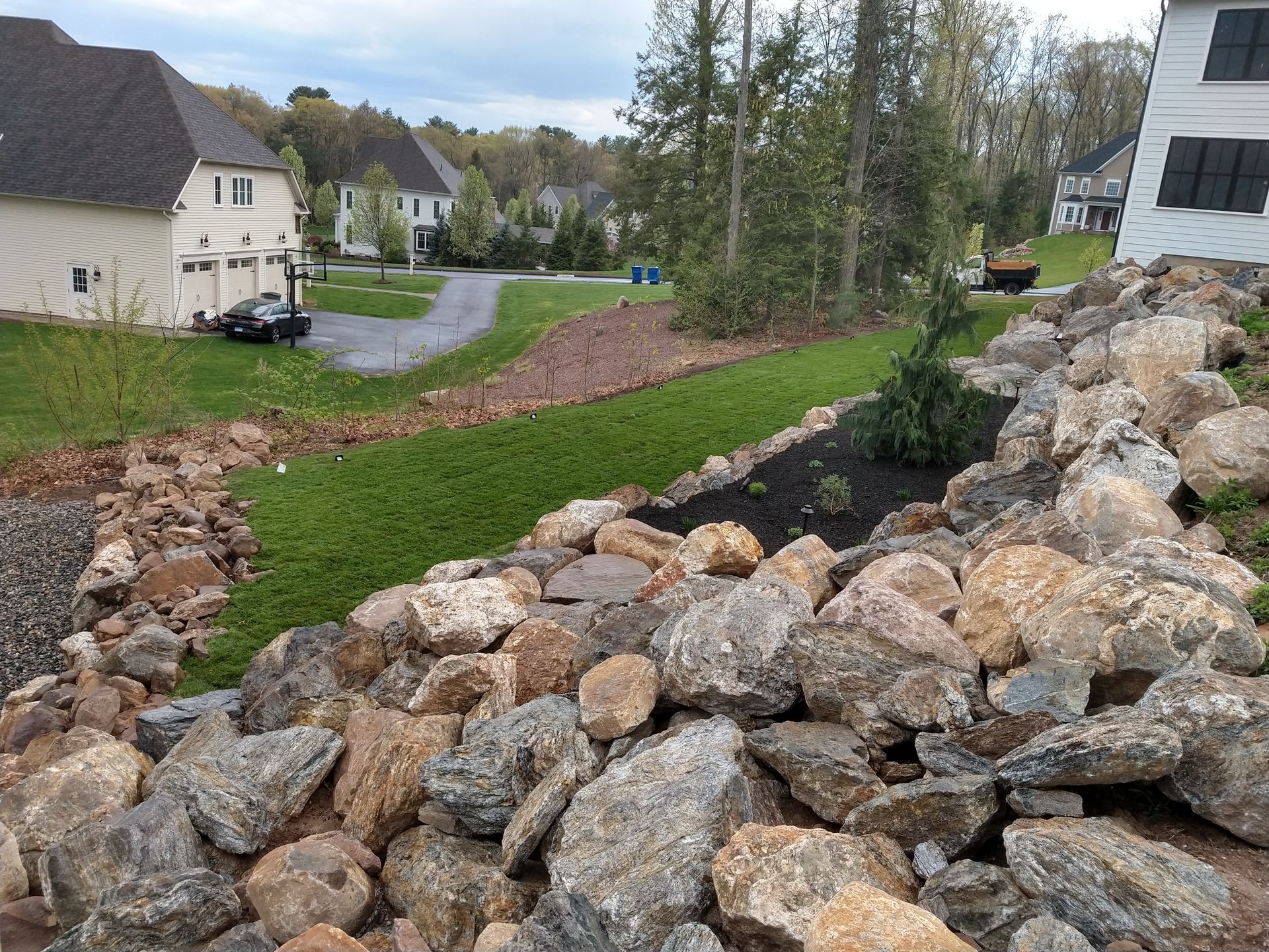 Rocky hillside with new sod and houses in the background.