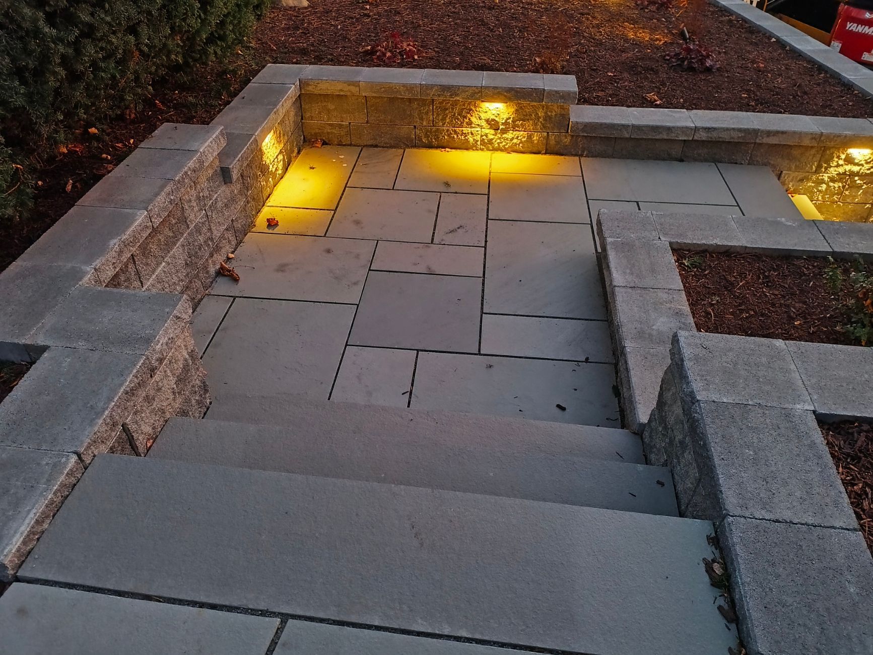 Stone steps and walkway illuminated by warm lights, flanked by retaining walls.