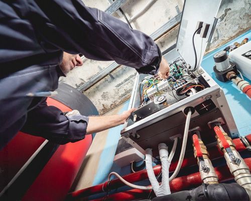 A man is working on a boiler in a factory.