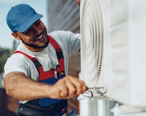 A man is working on an air conditioner with a wrench.