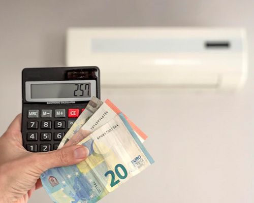 A person is holding a calculator and euro banknotes in front of an air conditioner.
