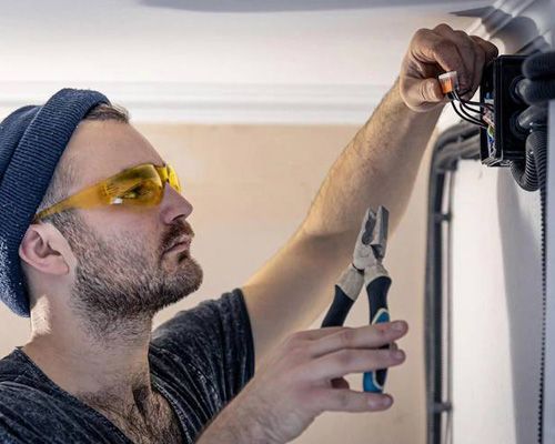 Arctic Fox technician wearing safety glasses and a hat is working on a garage door.