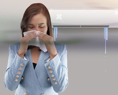 A woman is blowing her nose in front of an air conditioner.