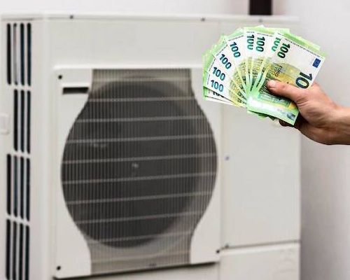 A person is holding a fan of money in front of an air conditioner.