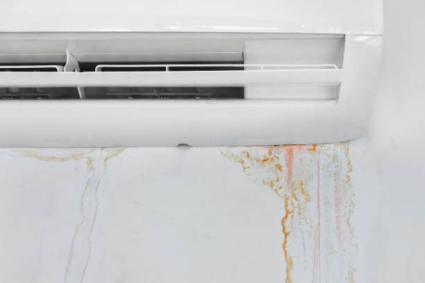 A white air conditioner is leaking water on a white wall.
