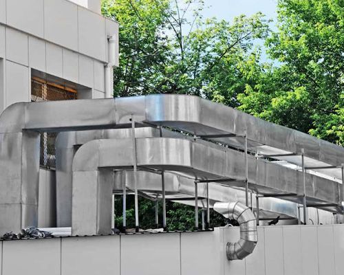 A large stainless steel pipe is hanging from the side of a building.