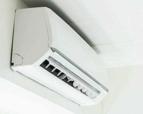 A white air conditioner is hanging from the ceiling in a room.