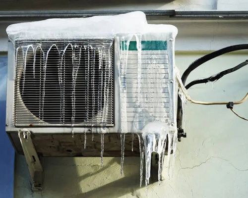The air conditioner is covered in snow and icicles.