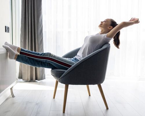 A woman is sitting in a chair with her feet up.
