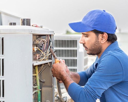 Arctic Fox technician in a blue hat is working on an air conditioner.