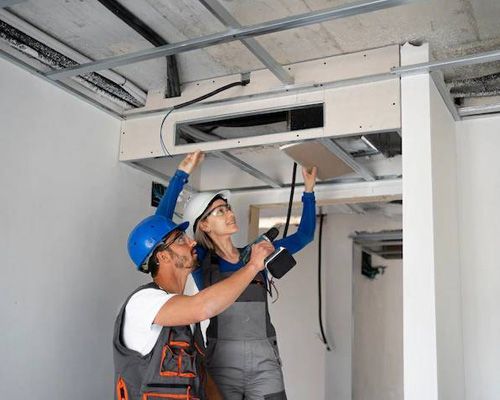 A man and a woman are working on a ceiling.