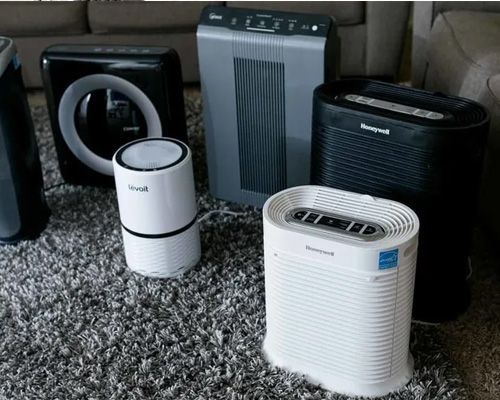 A group of air purifiers are sitting on a rug in a living room.
