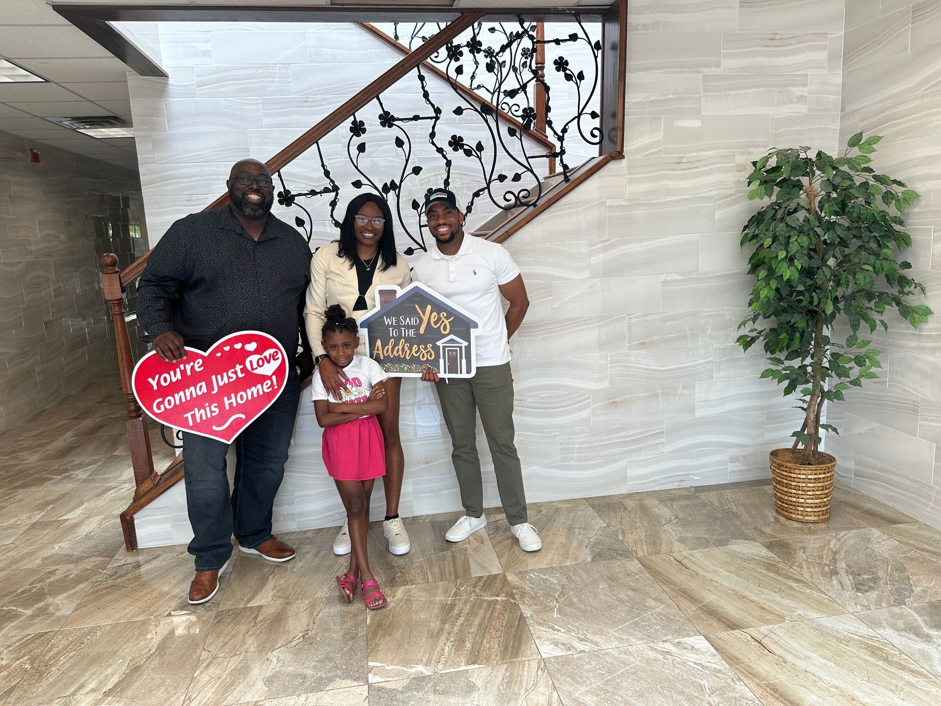 Family holding signs celebrating buying a new home inside a building.