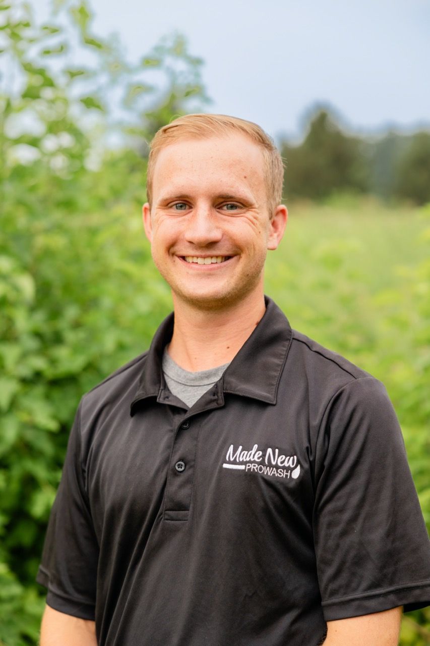 Smiling man in a black polo shirt standing outdoors in a green field