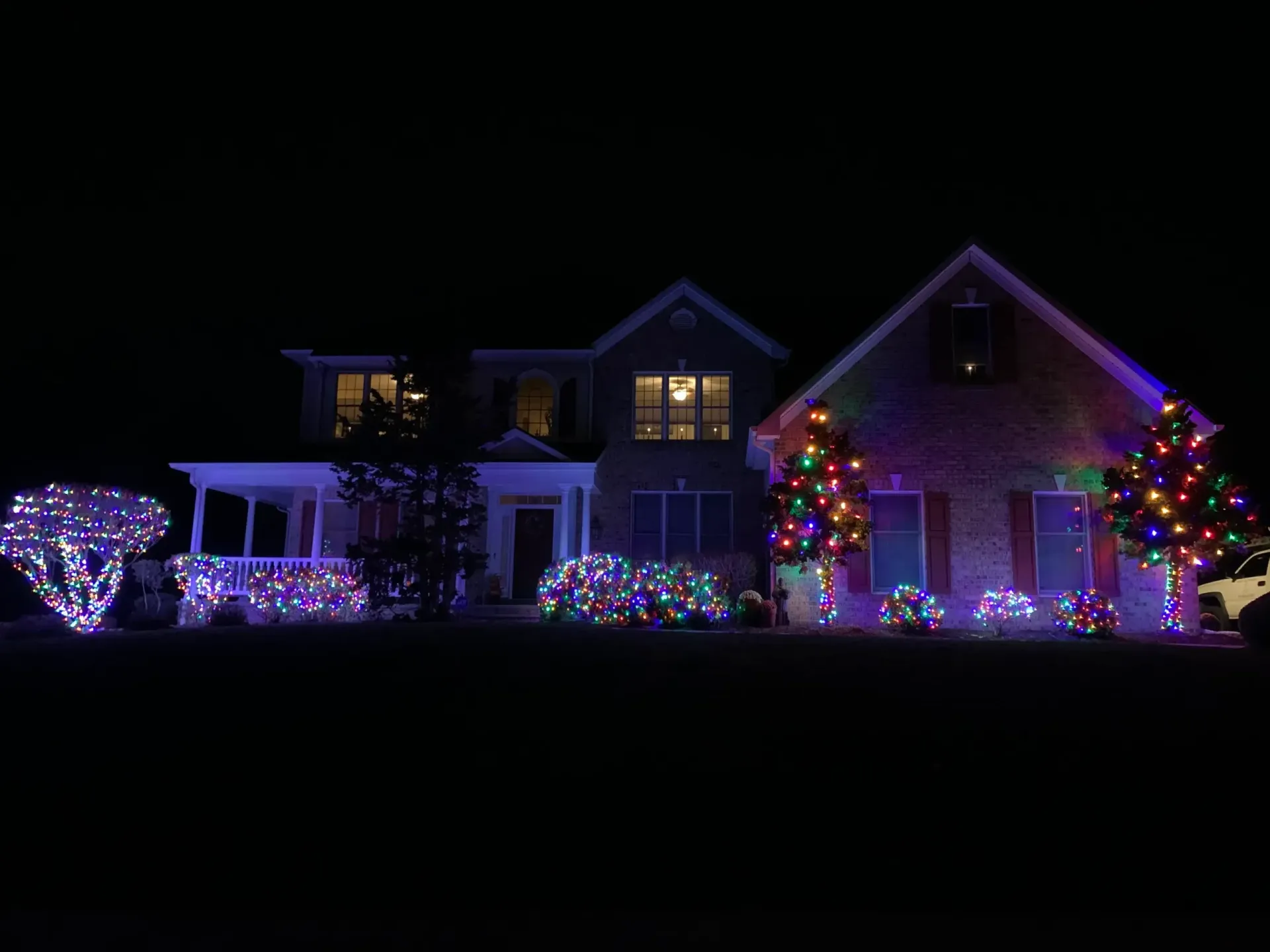 House at night covered in colorful Christmas lights and glowing holiday decorations