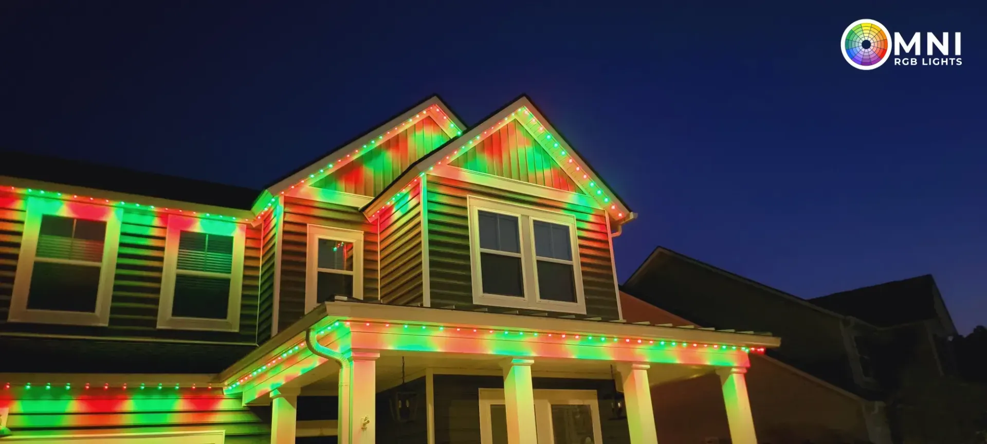 House outlined with red and green holiday lights at night