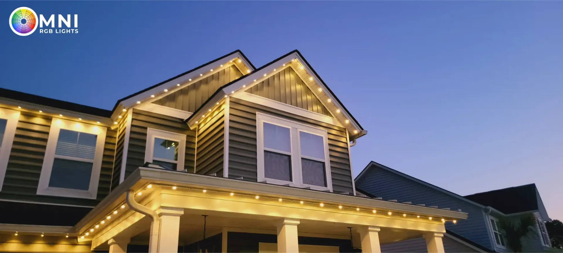 A house exterior at dusk with warm lights glowing along the roofline and porch.