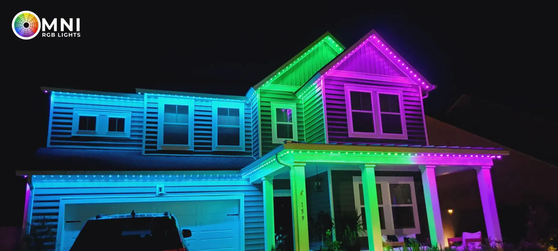 Suburban house lit with neon blue, green, and pink holiday lights at night